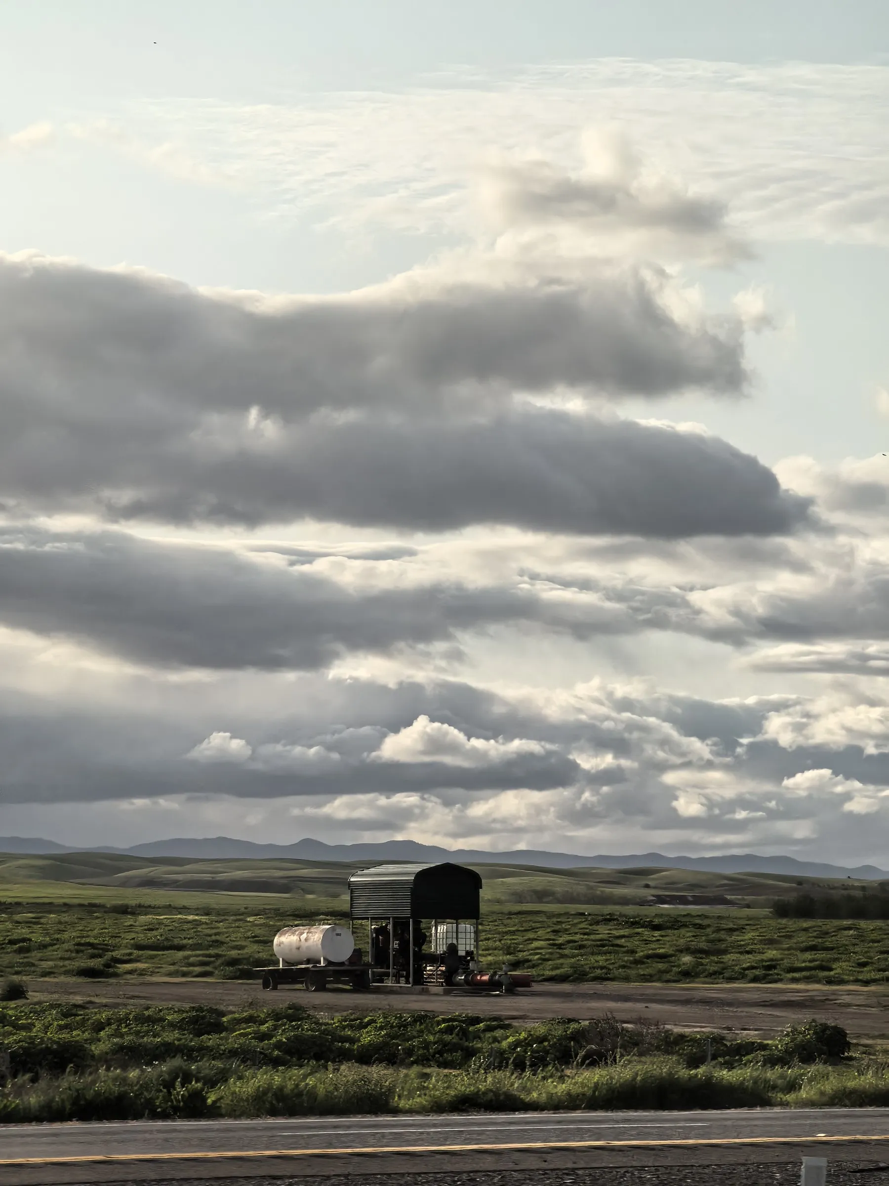 Utility truck parked on roadside with dramatic layered clouds over prairie landscape